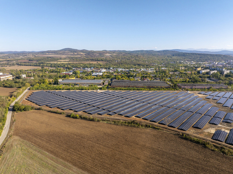 Aerial view of a large solar farm with rows of photovoltaic panels situated in a rural landscape near industrial buildings and the town of Lovech Lovech Bulgaria. Aerial view of a large solar farm with rows of photovoltaic panels situated in a rural landscape near industrial buildings and the town of Lovech Lovech Bulgaria.