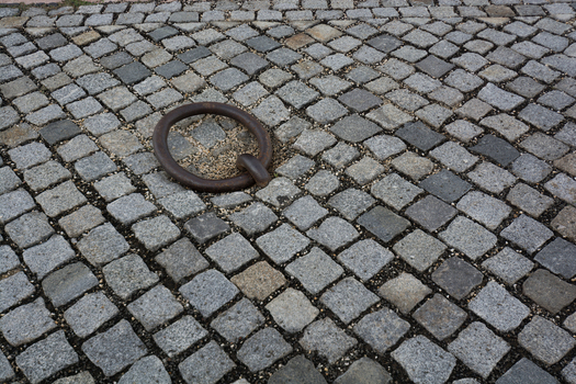 View of a weathered iron mooring ring embedded in traditional grey cobblestone pavement in Budapest Hungary.