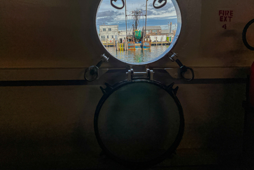 View of a fishing boat docked in the harbor as seen through a circular ship porthole on Block Island in New Shoreham Rhode Island United States.
