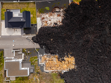 Aerial view of a lava flow from a volcanic eruption encroaching on residential houses in Iceland. Aerial view of a lava flow from a volcanic eruption encroaching on residential houses in Iceland.