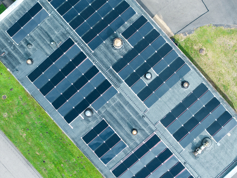 Aerial view of a flat roof covered with rows of solar panels featuring several roof vents and surrounded by green grass in Olaine Olaine Municipality Latvia. Aerial view of a flat roof covered with rows of solar panels featuring several roof vents and surrounded by green grass in Olaine Olaine Municipality Latvia.