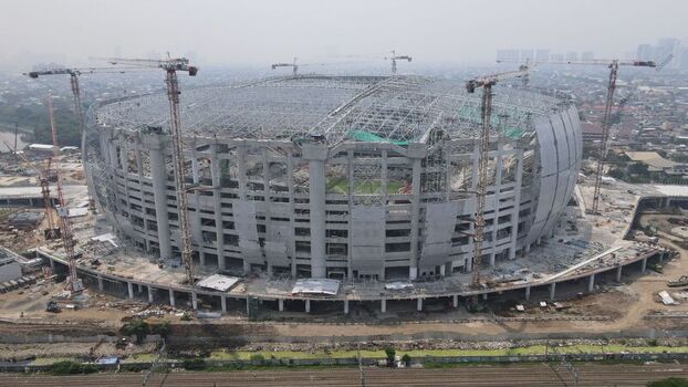 Aerial view of Jakarta International Stadium under construction featuring the massive concrete structure steel roof framework and multiple tower cranes in Tanjung Priok Jakarta Indonesia. Aerial view of Jakarta International Stadium under construction featuring the massive concrete structure steel roof framework and multiple tower cranes in Tanjung Priok Jakarta Indonesia.