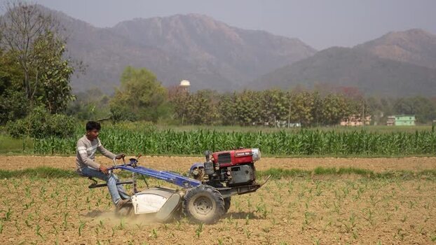 View of a farmer operating a power tiller in a field Nepal. View of a farmer operating a power tiller in a field Nepal.
