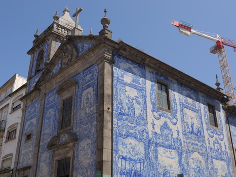 View of Capela das Almas a historic chapel adorned with intricate blue and white azulejo tiles with a construction crane visible in the background in Porto Porto District Portugal. View of Capela das Almas a historic chapel adorned with intricate blue and white azulejo tiles with a construction crane visible in the background in Porto Porto District Portugal.