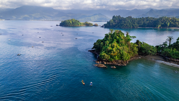 Aerial view of Prigi Beach featuring lush green islands calm blue waters and small fishing boats scattered across the bay in Kecamatan Watulimo Jawa Timur Indonesia. Aerial view of Prigi Beach featuring lush green islands calm blue waters and small fishing boats scattered across the bay in Kecamatan Watulimo Jawa Timur Indonesia.