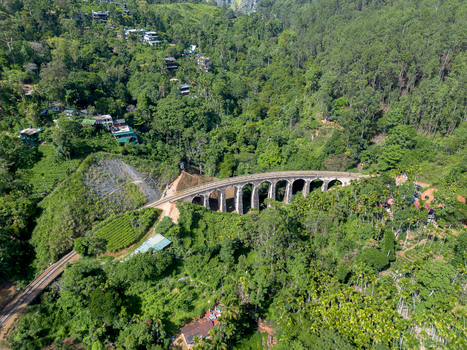 Aerial view of the Nine Arch Bridge surrounded by lush green tea plantations and dense forest in the hills of Demodara Uva Province Sri Lanka. Aerial view of the Nine Arch Bridge surrounded by lush green tea plantations and dense forest in the hills of Demodara Uva Province Sri Lanka.