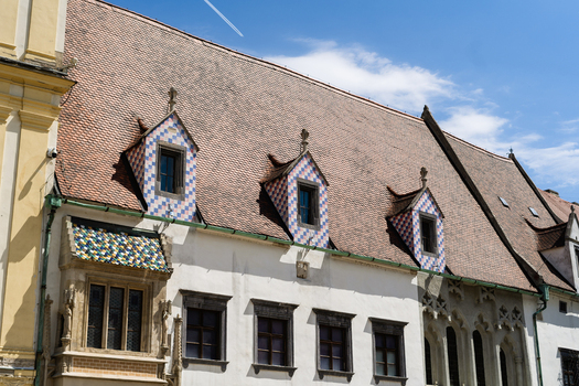 View of the historic Old Town Hall featuring colorful tiled roofs and decorative dormer windows under a clear blue sky in Bratislava Bratislava Region Slovakia. View of the historic Old Town Hall featuring colorful tiled roofs and decorative dormer windows under a clear blue sky in Bratislava Bratislava Region Slovakia.