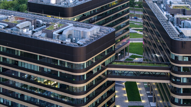 Aerial view of modern office buildings with glass facades dark horizontal bands green roofs and a connecting bridge in Poland. Aerial view of modern office buildings with glass facades dark horizontal bands green roofs and a connecting bridge in Poland.