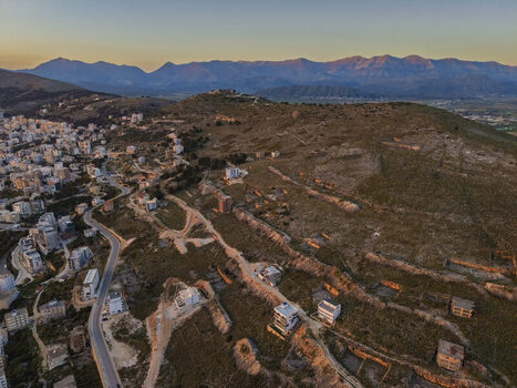 Aerial view of the coastal city of Saranda with urban development winding roads and rugged hills under the warm light of the golden hour. Saranda Vlore County Albania. Aerial view of the coastal city of Saranda with urban development winding roads and rugged hills under the warm light of the golden hour. Saranda Vlore County Albania.