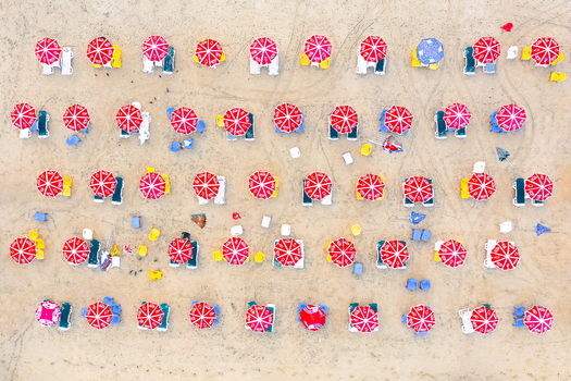 Aerial view of Bat Yam beach with people relaxing under organized rows of red and white umbrellas on the sand Bat Yam Center District Israel. Aerial view of Bat Yam beach with people relaxing under organized rows of red and white umbrellas on the sand Bat Yam Center District Israel.