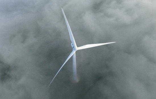 Aerial view of a single white wind turbine emerging from a thick layer of morning fog and low clouds in Netherlands. Aerial view of a single white wind turbine emerging from a thick layer of morning fog and low clouds in Netherlands.