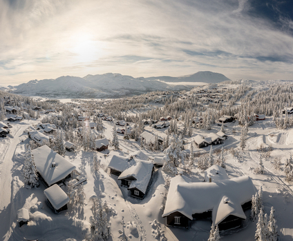 Aerial view of Gaustablikk Fjellresort surrounded by snow covered cabins pine trees and mountainous terrain under a bright winter sky in Rjukan Telemark Norway. Aerial view of Gaustablikk Fjellresort surrounded by snow covered cabins pine trees and mountainous terrain under a bright winter sky in Rjukan Telemark Norway.