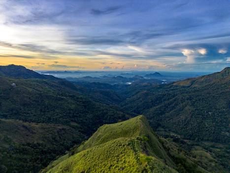 Aerial view of Little Adam s Peak surrounded by lush green mountains and rolling hills under a dramatic sunset sky in Badulla Uva Province Sri Lanka. Aerial view of Little Adam s Peak surrounded by lush green mountains and rolling hills under a dramatic sunset sky in Badulla Uva Province Sri Lanka.