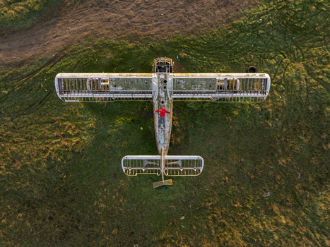 Aerial view of an abandoned airplane with a person in a red jacket standing on the fuselage in a grassy field during golden hour in Bulgaria. Aerial view of an abandoned airplane with a person in a red jacket standing on the fuselage in a grassy field during golden hour in Bulgaria.