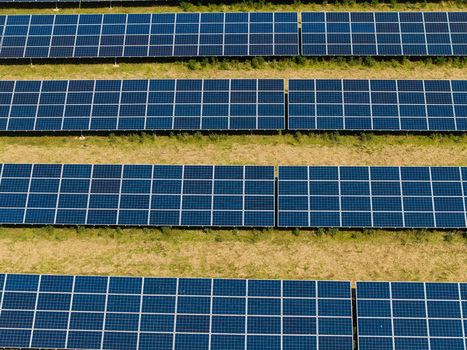 Aerial view of Lisburn Solar Farm with rows of blue photovoltaic panels arranged in neat lines across the grassy field in Lisburn Northern Ireland United Kingdom. Aerial view of Lisburn Solar Farm with rows of blue photovoltaic panels arranged in neat lines across the grassy field in Lisburn Northern Ireland United Kingdom.