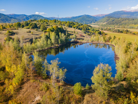 Aerial view of the Gudronove jamy acid tar lagoons surrounded by autumn trees and rolling hills under the Low Tatras mountains in Predajna Banskobystricky kraj Slovakia. Aerial view of the Gudronove jamy acid tar lagoons surrounded by autumn trees and rolling hills under the Low Tatras mountains in Predajna Banskobystricky kraj Slovakia.
