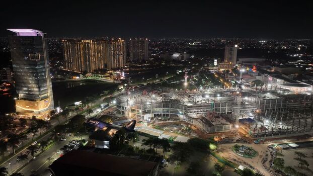 Aerial view of Summarecon Bekasi at night featuring illuminated high rise buildings an active construction site and urban infrastructure in Kecamatan Medan Satria Jawa Barat Indonesia.