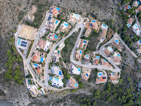 Aerial view of residential villas with swimming pools and winding roads in the coastal landscape of Moraira Valencian Community Spain.