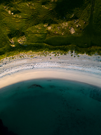 Aerial view of a curved sandy beach with turquoise water and green grassy hills in Leknes Nordland Norway. Aerial view of a curved sandy beach with turquoise water and green grassy hills in Leknes Nordland Norway.