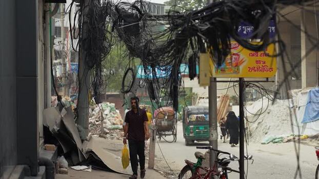 View of tangled overhead cables and street life in Dhaka Bangladesh.