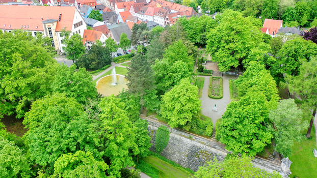 Aerial view of Stadtpark featuring lush green trees historic red roofed buildings and stone fortifications in Forchheim Bayern Germany. Aerial view of Stadtpark featuring lush green trees historic red roofed buildings and stone fortifications in Forchheim Bayern Germany.