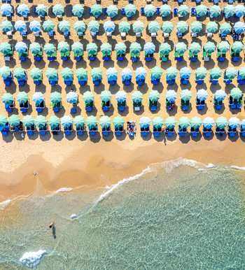 Aerial view of Bat Yam beach featuring rows of turquoise and blue umbrellas on golden sand by clear Mediterranean water in Bat Yam Center District Israel. Aerial view of Bat Yam beach featuring rows of turquoise and blue umbrellas on golden sand by clear Mediterranean water in Bat Yam Center District Israel.