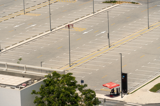 Aerial view of an empty outdoor parking lot with white painted lines tall light poles and a person sitting under a red umbrella in Dubai Dubai United Arab Emirates. Aerial view of an empty outdoor parking lot with white painted lines tall light poles and a person sitting under a red umbrella in Dubai Dubai United Arab Emirates.