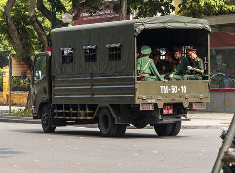 Hanoi Vietnam 11 November 2025 View of military personnel in uniform sitting in the back of a green transport truck near the Imperial Citadel of Thang Long.