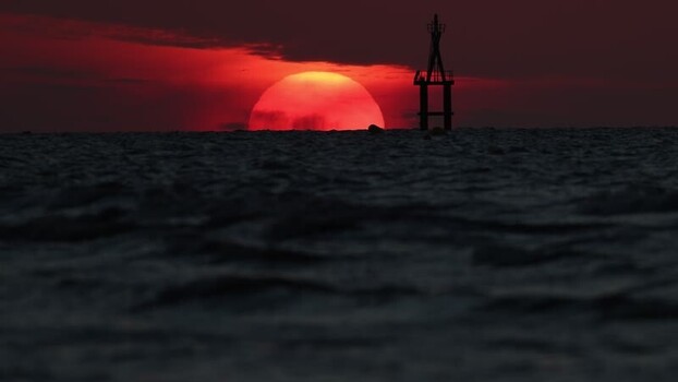 View of a dramatic red sunset over the sea with a buoy France.
