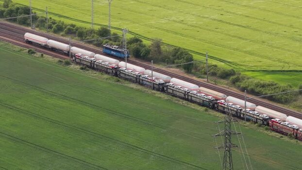 Aerial view of a freight train carrying cars through fields Czechia. Aerial view of a freight train carrying cars through fields Czechia.