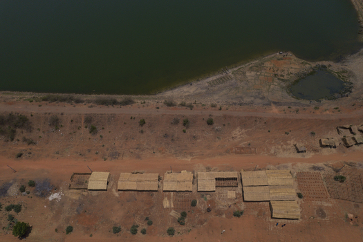 Aerial view of Minjibir shoreline with straw roofed huts along a dirt road and dark green water in Kano Kano State Nigeria. Aerial view of Minjibir shoreline with straw roofed huts along a dirt road and dark green water in Kano Kano State Nigeria.