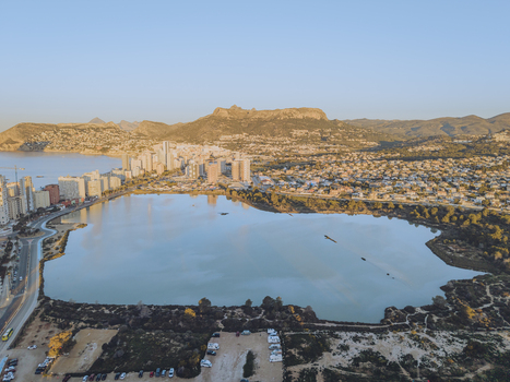 Aerial view of the Las Salinas salt lake in Calp surrounded by modern high rise buildings coastal hills and lush vegetation. Calp Valencian Community Spain. Aerial view of the Las Salinas salt lake in Calp surrounded by modern high rise buildings coastal hills and lush vegetation. Calp Valencian Community Spain.