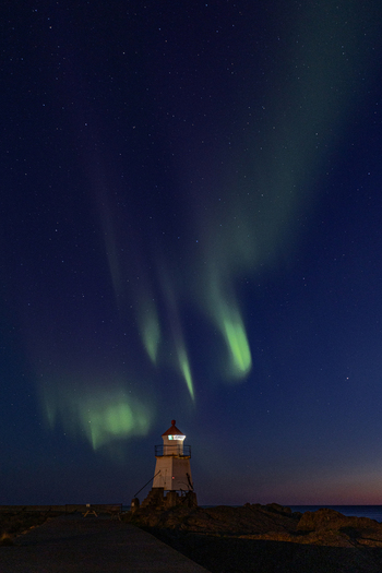 View of Laukvik fyr lighthouse under the vibrant green Aurora Borealis and a starry night sky in Laukvik Nordland Norway. View of Laukvik fyr lighthouse under the vibrant green Aurora Borealis and a starry night sky in Laukvik Nordland Norway.
