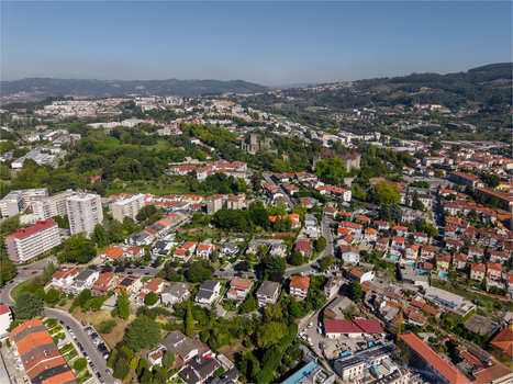 Aerial view of Guimaraes Castle and the historic Paco dos Duques de Braganca surrounded by residential neighborhoods and green spaces in Guimaraes Braga Portugal. Aerial view of Guimaraes Castle and the historic Paco dos Duques de Braganca surrounded by residential neighborhoods and green spaces in Guimaraes Braga Portugal.