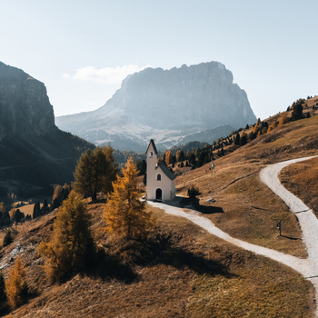 Aerial view of Cappella di San Maurizio surrounded by golden autumn trees and the majestic rocky peaks of the Dolomites in Selva di Val Gardena Trentino Alto Adige Italy. Aerial view of Cappella di San Maurizio surrounded by golden autumn trees and the majestic rocky peaks of the Dolomites in Selva di Val Gardena Trentino Alto Adige Italy.
