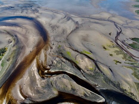 Aerial view of the intricate sand patterns and winding water channels of Findhorn Bay under bright daylight in Findhorn Scotland United Kingdom. Aerial view of the intricate sand patterns and winding water channels of Findhorn Bay under bright daylight in Findhorn Scotland United Kingdom.