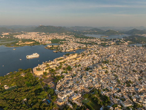 Aerial view of the City Palace complex situated on the banks of Lake Pichola surrounded by the dense urban landscape of Udaipur Rajasthan India.