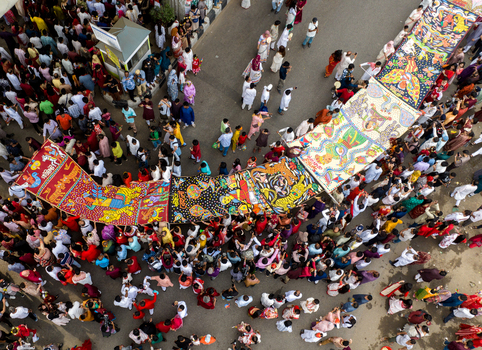 Dhaka Bangladesh 13 April 2026 Aerial view of a lively cultural procession with a dense crowd admiring vibrant traditional artworks on a grey street.