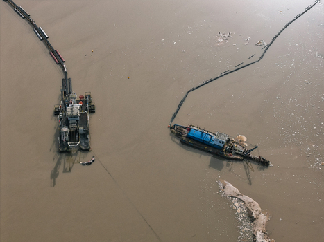 Aerial view of two industrial dredgers operating on a murky river with long floating pipes extending across the water surface in Dulmen North Rhine Westphalia Germany. Aerial view of two industrial dredgers operating on a murky river with long floating pipes extending across the water surface in Dulmen North Rhine Westphalia Germany.