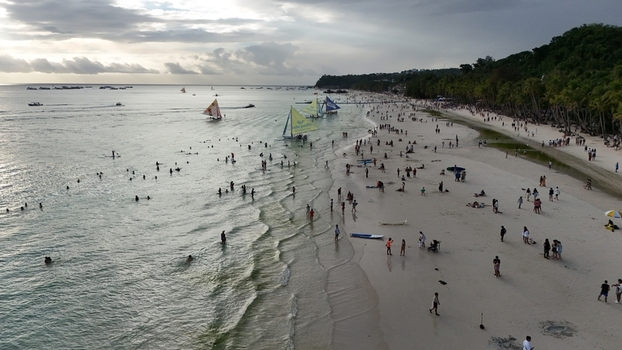 Malay Philippines 02 May 2026 Aerial view of Boracay Island featuring the crowded white sand beach with sailboats and people swimming under a cloudy sky.