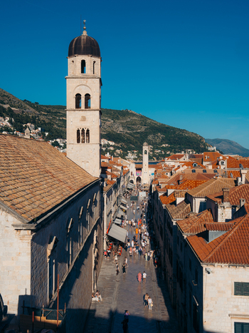 View of Dubrovnik Old Town with the Franciscan Monastery bell tower overlooking the crowded Stradun street and historic red tiled rooftops in Dubrovnik Dubrovnik Neretva County Croatia. View of Dubrovnik Old Town with the Franciscan Monastery bell tower overlooking the crowded Stradun street and historic red tiled rooftops in Dubrovnik Dubrovnik Neretva County Croatia.