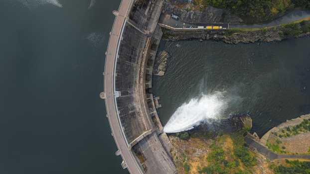 Aerial view of Barrage de Villerest with water discharging from the spillway into the river surrounded by rocky terrain and lush greenery in Commelle Vernay Auvergne Rhone Alpes France. Aerial view of Barrage de Villerest with water discharging from the spillway into the river surrounded by rocky terrain and lush greenery in Commelle Vernay Auvergne Rhone Alpes France.