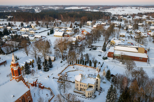 Aerial view of the snow covered village and the red brick church tower surrounded by bare trees in winter in Kernave Vilnius County Lithuania.