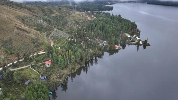 Aerial view of Corani Lake surrounded by dense pine forests rolling hills and small cabins along the shoreline in Chapare Cochabamba Department Bolivia. Aerial view of Corani Lake surrounded by dense pine forests rolling hills and small cabins along the shoreline in Chapare Cochabamba Department Bolivia.