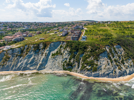 Aerial view of the steep coastal cliffs and sandy beach in Byala with residential buildings perched on the grassy plateau above the Black Sea. Byala Varna Bulgaria. Aerial view of the steep coastal cliffs and sandy beach in Byala with residential buildings perched on the grassy plateau above the Black Sea. Byala Varna Bulgaria.