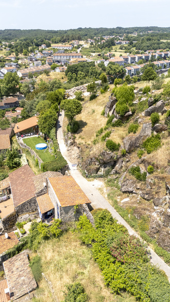 Aerial view of a historic town with stone houses terracotta rooftops and rocky terrain surrounded by lush greenery in Allariz Province of Ourense Spain. Aerial view of a historic town with stone houses terracotta rooftops and rocky terrain surrounded by lush greenery in Allariz Province of Ourense Spain.