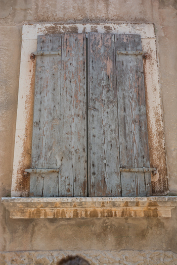 View of a weathered wooden window shutter on a rustic stone wall in the historic old town of Rovinj Istria County Croatia. View of a weathered wooden window shutter on a rustic stone wall in the historic old town of Rovinj Istria County Croatia.