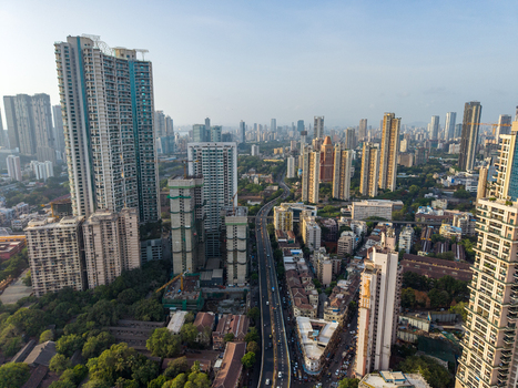 Aerial view of the dense urban skyline of Mumbai featuring modern high rise residential towers a busy highway and lush green trees in Mumbai Maharashtra India. Aerial view of the dense urban skyline of Mumbai featuring modern high rise residential towers a busy highway and lush green trees in Mumbai Maharashtra India.