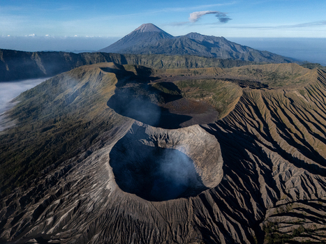 Aerial view of Mount Bromo with its volcanic crater rugged landscape and surrounding peaks under a clear blue sky in Kecamatan Sukapura Jawa Timur Indonesia.