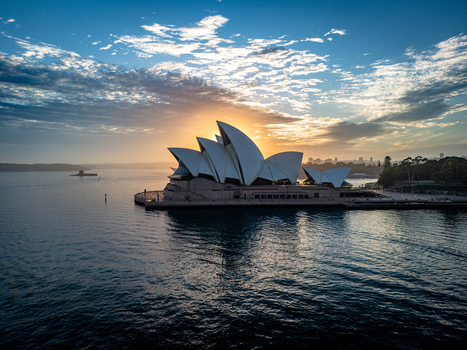 Aerial view of the iconic Sydney Opera House basking in the golden glow of the sunrise its white sails contrasting with the deep blue harbor Sydney New South Wales Australia. Aerial view of the iconic Sydney Opera House basking in the golden glow of the sunrise its white sails contrasting with the deep blue harbor Sydney New South Wales Australia.